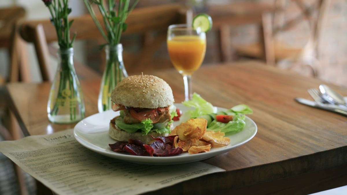 Hamburguesa servida con ensalada en la mesa de un restaurante — cómo comer los días difíciles sin culpa
