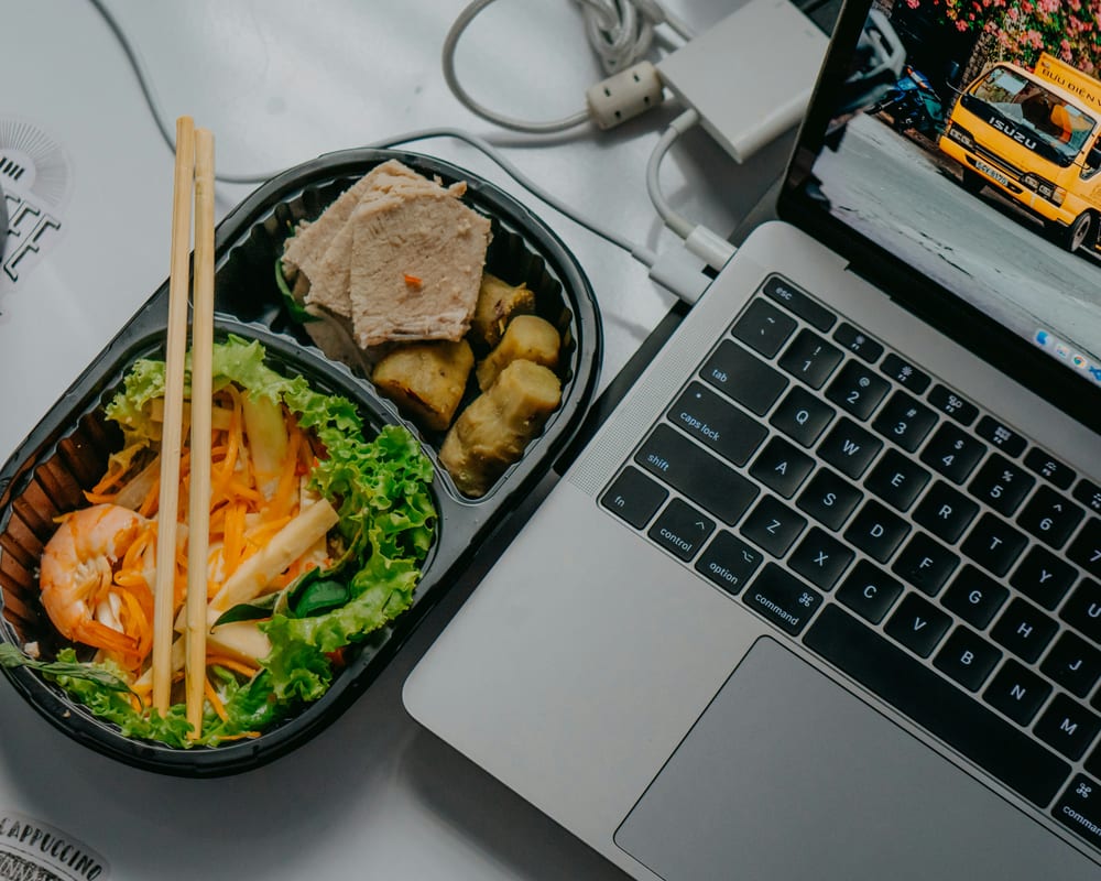 Comida balanceada junto a una laptop — consulta de nutrición en línea sin salir de casa o del trabajo